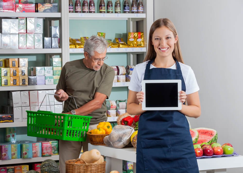 Saleswoman Holding a Tablet in Front of a Customer