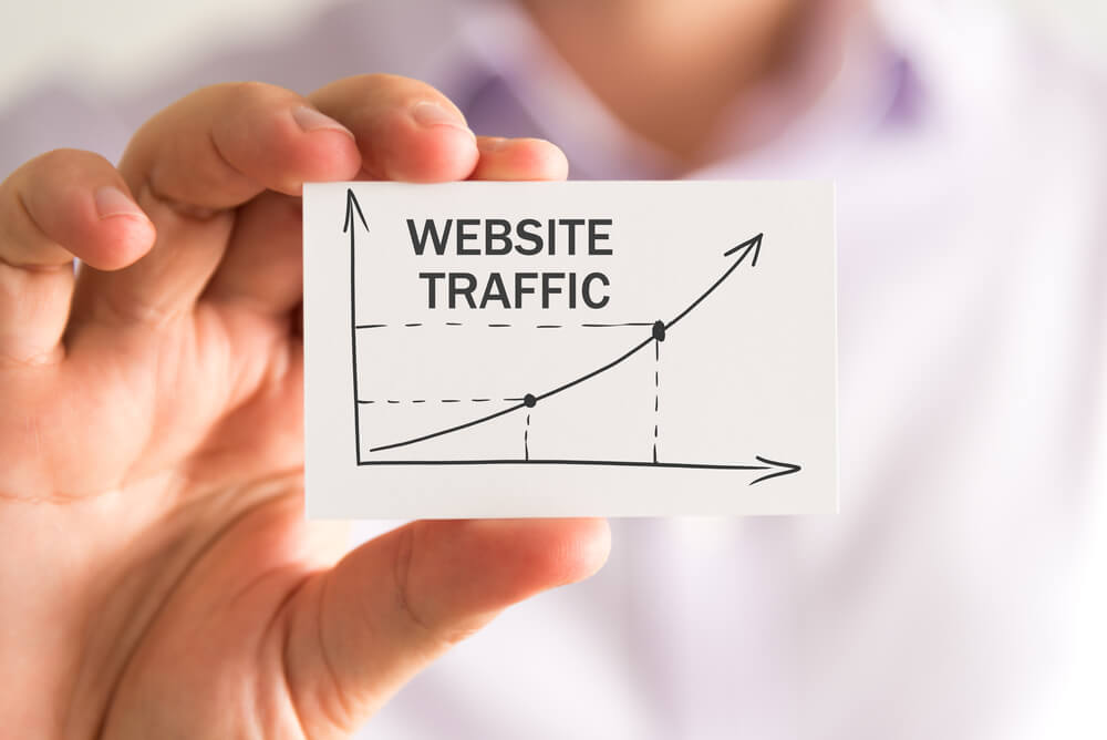 Closeup on Businessman Holding a Card With Website Traffic Rising Arrow and Chart