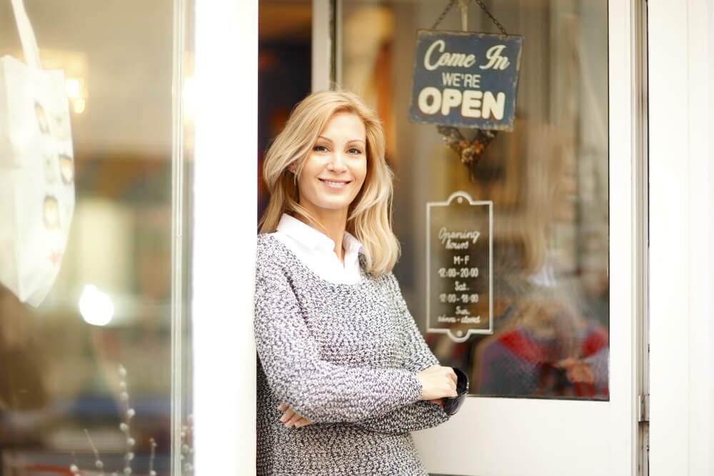 Portrait of Attractive Clothing Store Owner Standing in Her Shop Entrance.