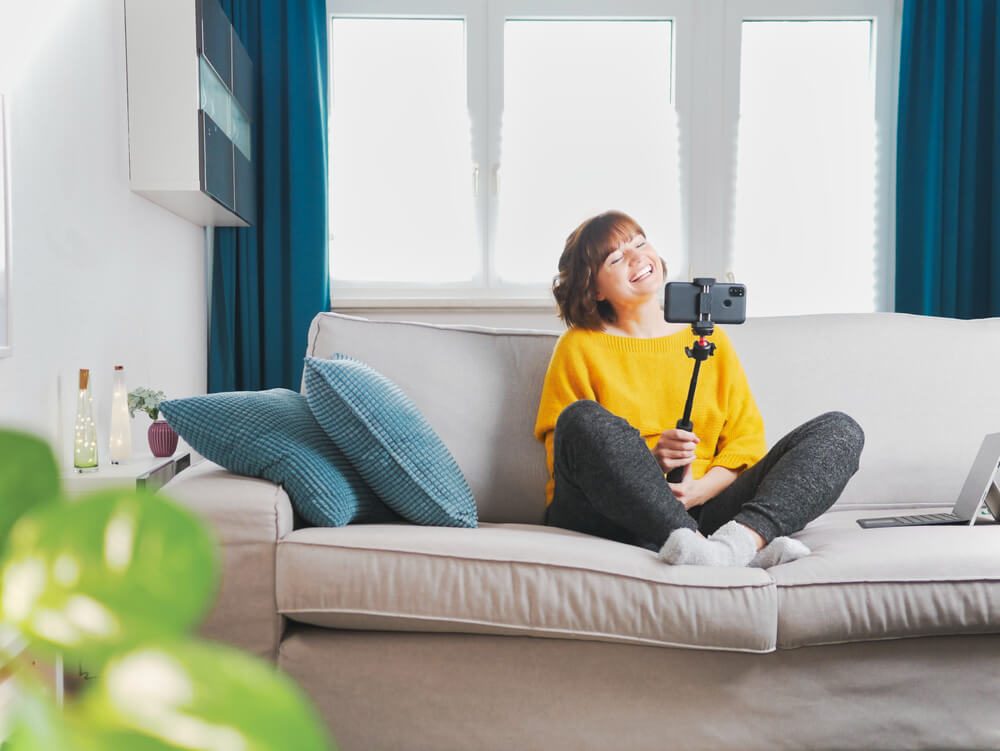Woman Blogger Sitting on Sofa and Talking With Followers in Live Streaming With Smartphone.