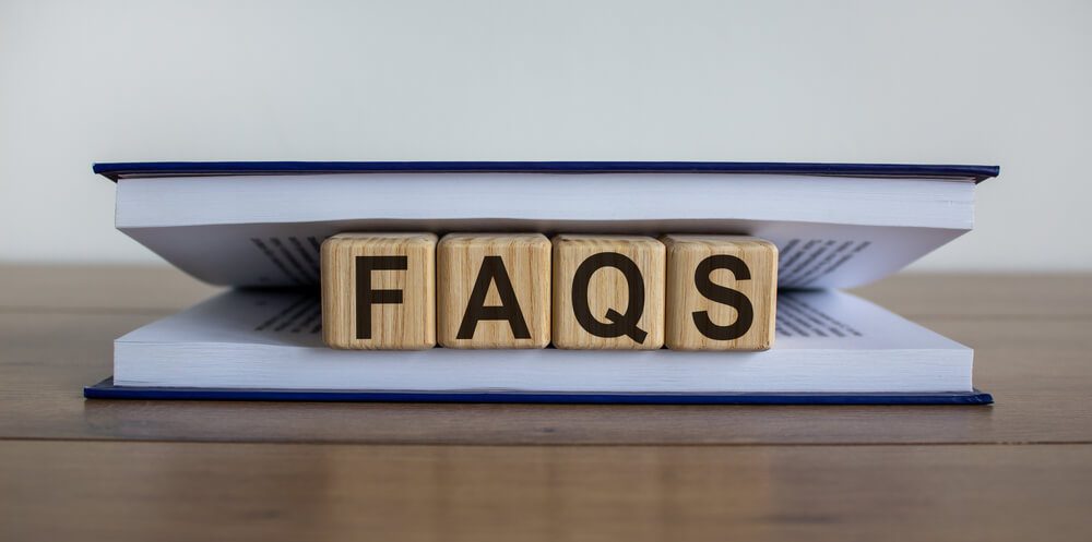 Concept Word ‘FAQS’ on Wooden Circles Between Pages of a Book on a Beautiful Wooden Table