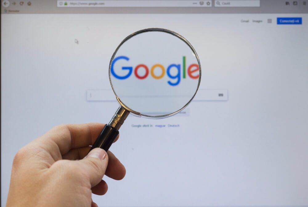 Google Homepage on the Screen Under a Magnifying Glass.